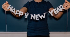 Image of a person holding up a "Happy New Year" paper garland.