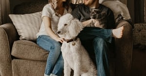 Couple sitting on a couch with a dog.