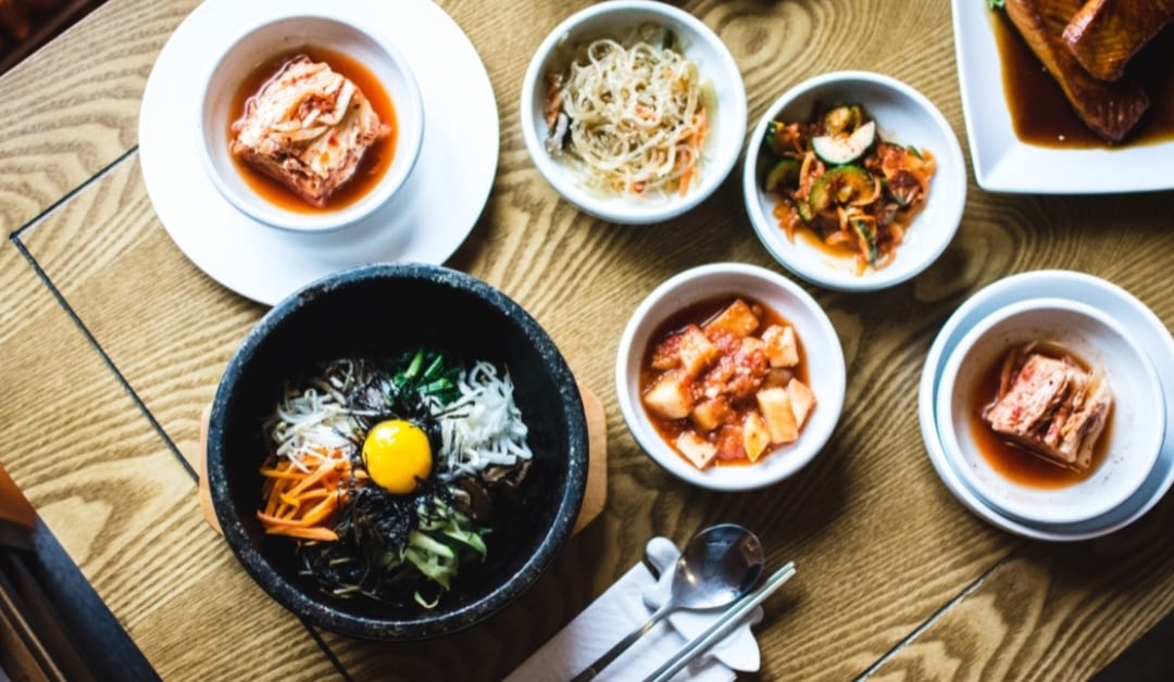 Aerial view of a table covered in Korean dishes, including bibimbap.