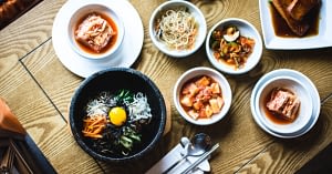Aerial view of a table covered in Korean dishes, including bibimbap.